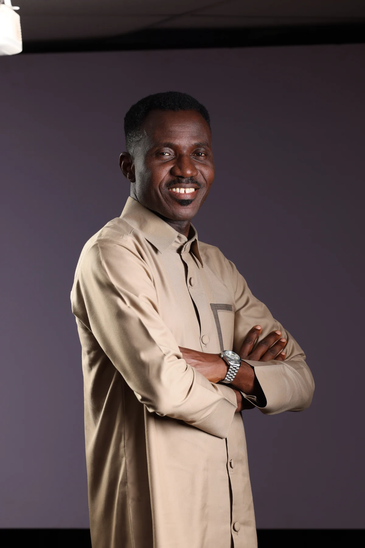 Kayode Braimoh smiling with his arms folded