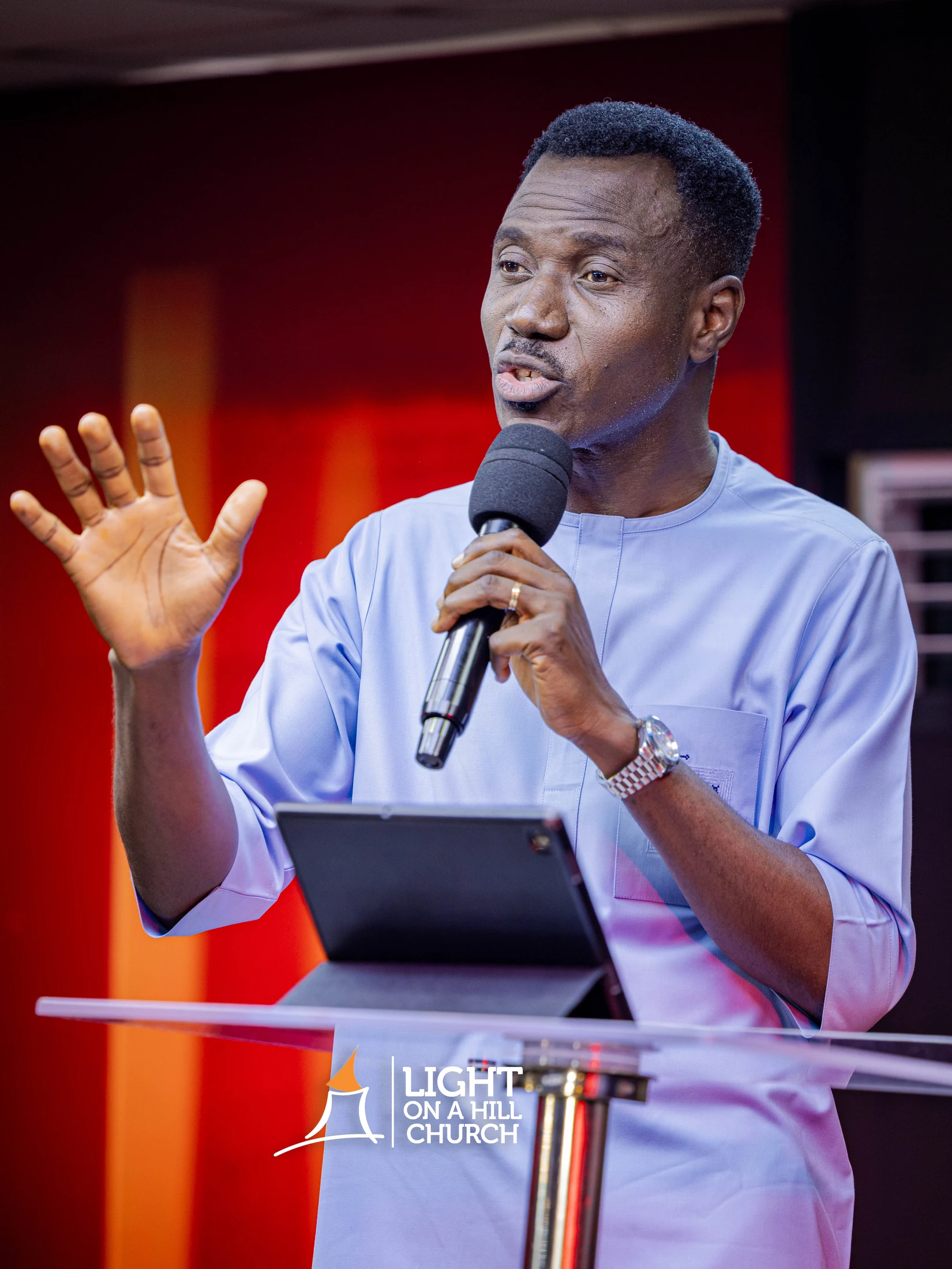 Kayode Braimoh teaching in a light blue tunic, positioned to the right of the frame.